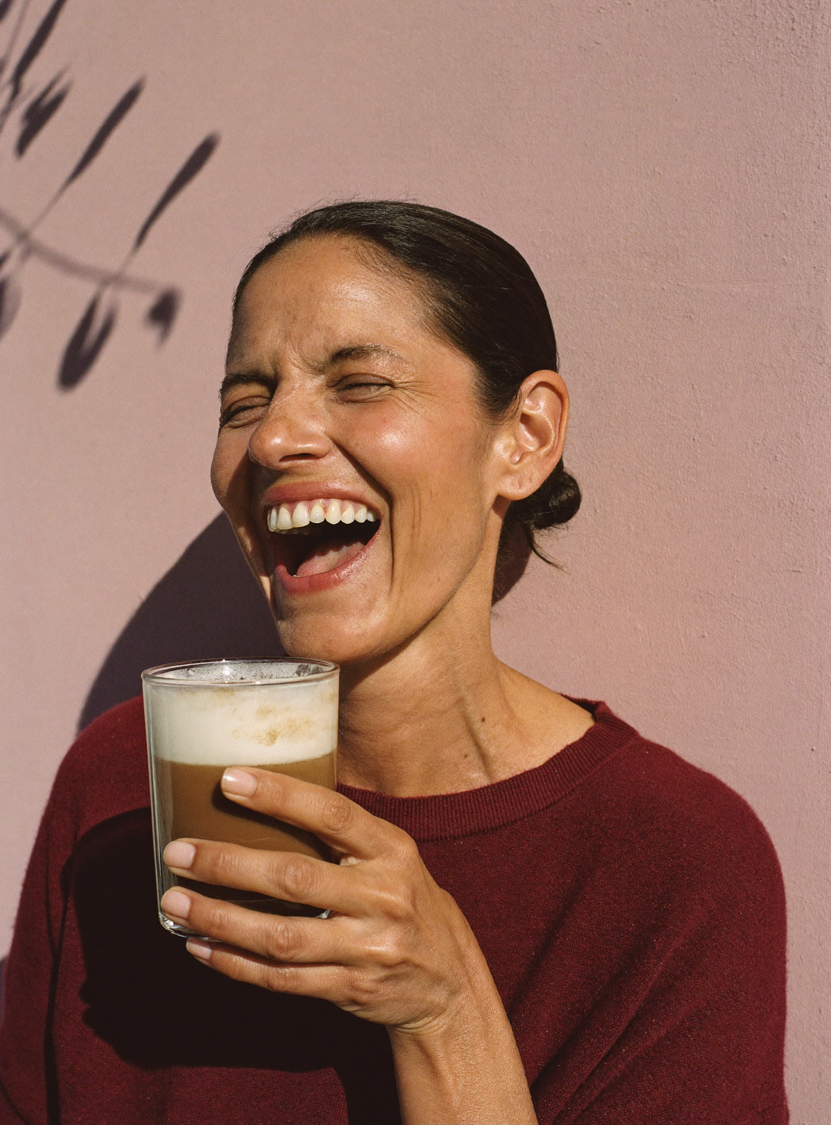 Une femme rit au soleil, un shake Josie mousseux à la main